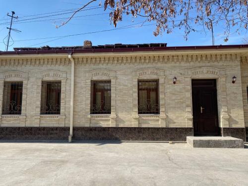 a white brick building with windows and a black door at Crown Samarkand in Samarkand