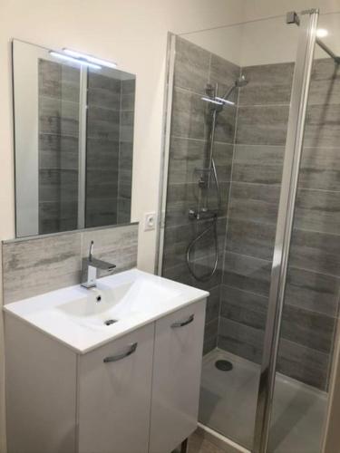 une salle de bain avec un lavabo blanc et une douche dans l'établissement T3 climatisé à 10 min des plages, à Perpignan