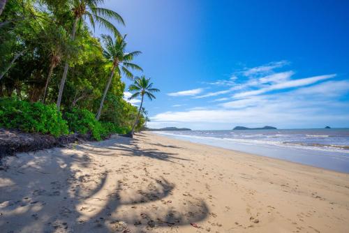 a beach with palm trees and footprints in the sand at Belle Escapes Beachfront Luxury Home 53 Arlington Clifton Beach in Palm Cove