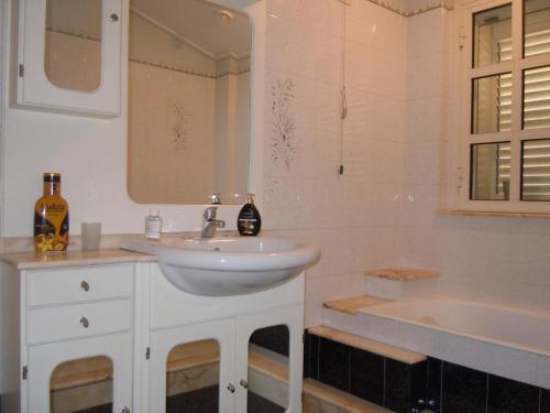 La salle de bains est pourvue d'un lavabo, d'une baignoire et d'un miroir. dans l'établissement Tonnara apartment 1st floor codi facing the sea with view - wi-fi, à Avola