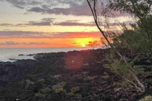 a sunset over the ocean on a rocky beach at La Trinité, charme historique du Sud Sauvage in Saint-Philippe