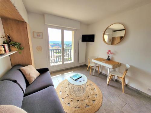 un salon avec un canapé et une table dans l'établissement M2M Studio magnifique vue mer - avec balcon - les pieds dans l eau!, à Blonville-sur-Mer