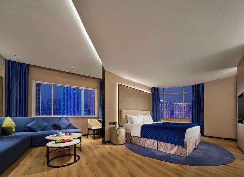 a hotel room with a bed and a blue couch at Vance Hotel - Taizhou in Taizhou