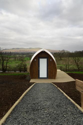 a small building with a door on a gravel road at Endrick Escape - Luxury Glamping in Gartness