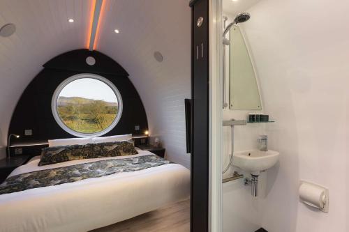 1 dormitorio con cama, ventana y lavamanos en Endrick Escape - Luxury Glamping, 