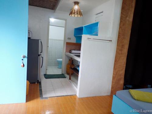 a kitchen with a white refrigerator and a bathroom at Blue Lagoon Guest house for Backpakers in Puerto Galera