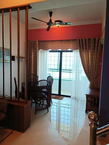 a living room with a ceiling fan and a table and chairs at My Getaway Home @Marina Cove in Lumut