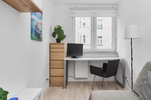 a desk with a computer in a room with a window at Charming Family Apartment in Wroclaw by Renters in Wrocław