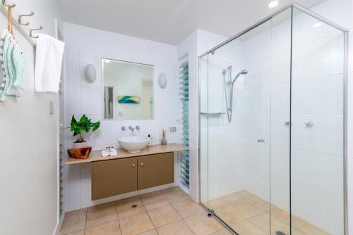 a bathroom with a glass shower and a sink at Seascape Holidays Villas on Murphy Street in Port Douglas