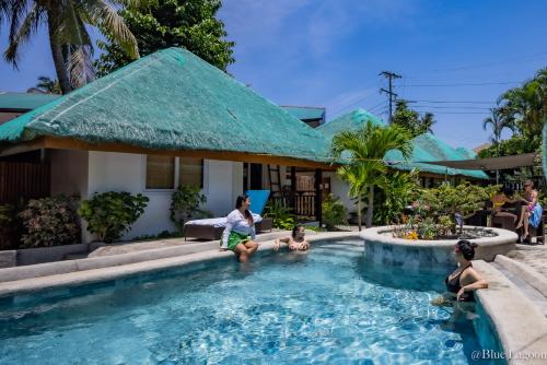 a woman and two children sitting in a swimming pool at Blue Lagoon Guest house for Backpakers in Puerto Galera