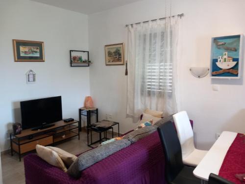 a living room with a couch and a tv at Kuća za odmor Skalina - Sea view in Splitska