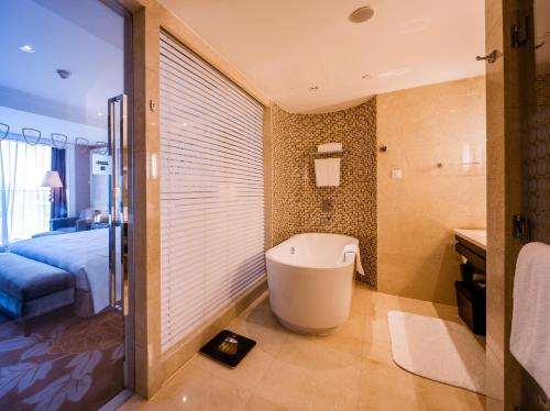 a bathroom with a bath tub and a bedroom at Tonino Lamborghini Hotel Kunshan City Center in Kunshan