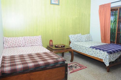 a living room with two beds and a table at Misty Retreat (Pragati House) in Madikeri