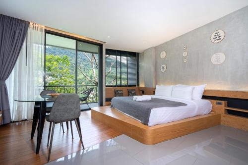 1 dormitorio con cama, escritorio y mesa en Natural Park Studio B24 with Magical Forest View, 5 Min to Kamala Beach & Phuket FantaSea, en Kamala Beach