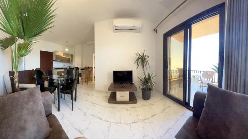 uma sala de estar com um sofá e uma mesa com uma televisão em My Sky Sea View 1 Bedroom Apartment em Hurghada