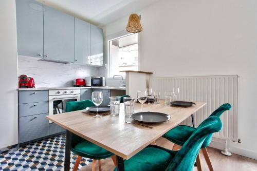 une cuisine avec une table en bois et des chaises vertes dans l'établissement Appartement Quartier Panthéon Free Netflix, à Paris