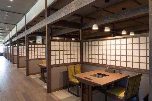 a restaurant with white walls and wooden tables and chairs at Jozankei Onsen Yurakusoan in Jozankei