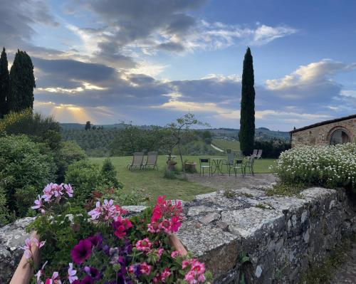 a garden with flowers and a stone wall at Torre Di Ponzano in Barberino di Val dʼElsa