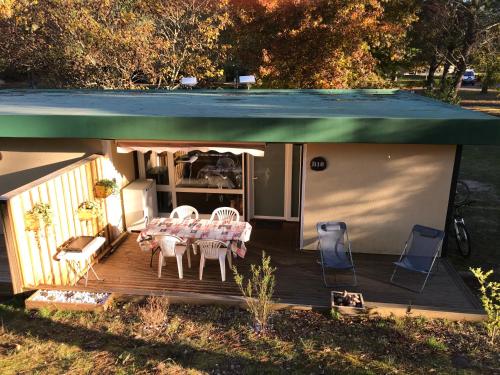 un patio avec une table et des chaises sur une terrasse dans l'établissement Village Vacances aux Villages sous les Pins, à Léon