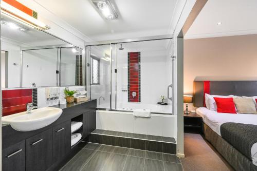 a bathroom with a sink and a shower and a bed at Platinum International in Toowoomba