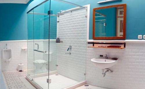 een badkamer met een glazen douche en een wastafel bij Tirtodipuran Hotel Yogyakarta in Timuran