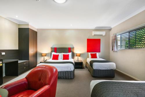 a hotel room with two beds and a red chair at Platinum International in Toowoomba