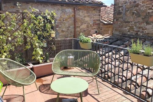 drie stoelen en een tafel op een balkon met planten bij La tua casa nel Chianti in San Donato in Poggio