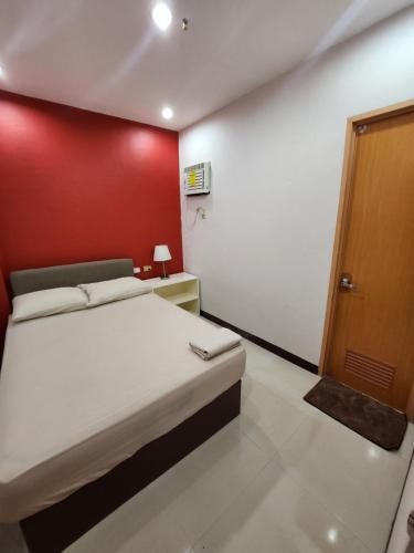 a bedroom with a bed and a red wall at MANTRA PENSIONNE Standard Room in Cagayan de Oro