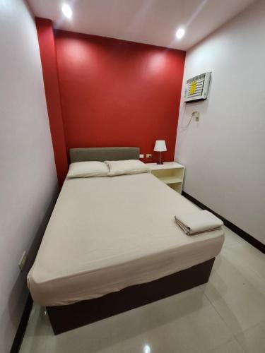 a bed in a room with a red wall at MANTRA PENSIONNE Standard Room in Cagayan de Oro
