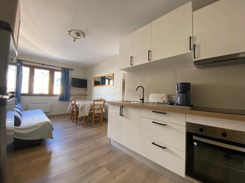 a kitchen with white cabinets and a living room at Gran Duc Pedrous in Pas de la Casa