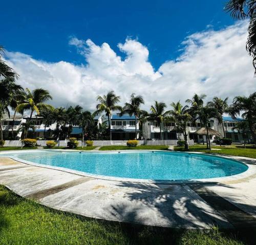 an empty swimming pool with palm trees and houses at Villa sur la plage de Mont-Choisy in Trou aux Biches