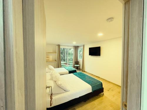 a hotel room with two beds and a television at Hotel Campestre Villa Mary in Santa Rosa de Cabal