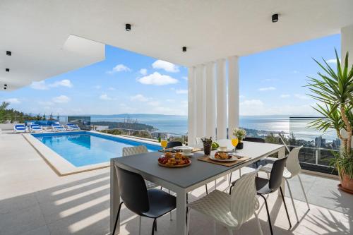 a dining room with a table and a swimming pool at Luxury Villa Sagnia, 4 en-suite bedrooms, sea views in Makarska