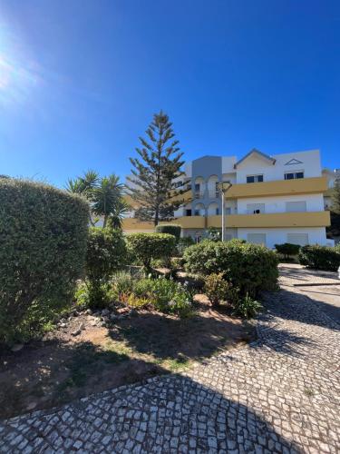 a building with a tree and bushes in front of it at Charming Salema in Salema