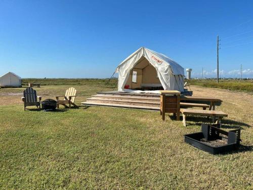 a tent in a field with benches and tables at Tentrr State Park Site - Texas Galveston Island- Beachside E - Single Camp in Galveston