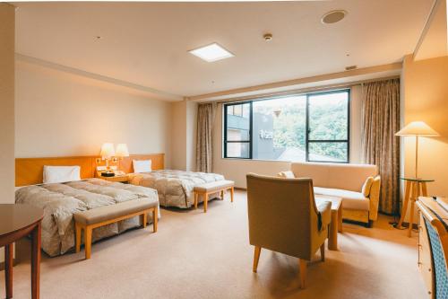 a hotel room with two beds and a window at Hotel Gyokusen in Matsue