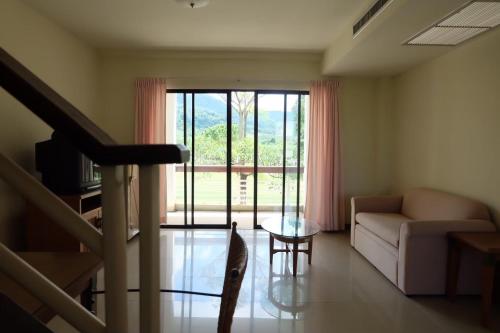 a living room with a couch and a table and a window at Samerdrow Khao Yai in Mu Si