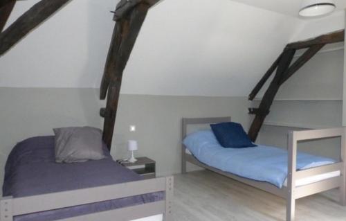 two beds in a room with wooden beams at Gite de Saint Jean in Saint-Jean-de-Thouars