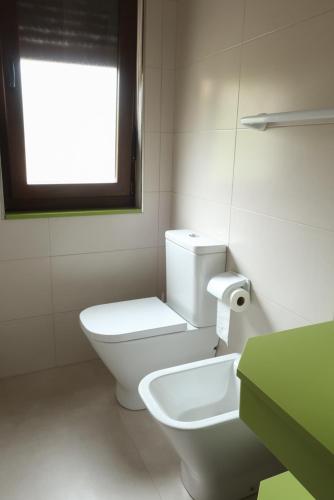 a white bathroom with a toilet and a window at Casa Balbi in Canales