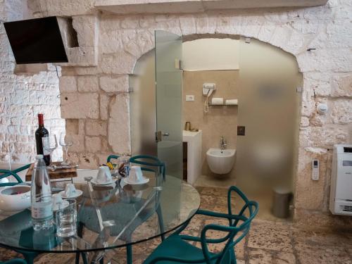 a glass table and chairs in a room with a bathroom at Dama Bianca Boutique Hotel Ostuni in Ostuni