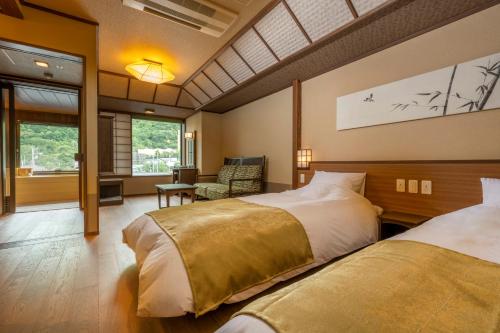 a hotel room with two beds and a chair at Jozankei Onsen Yurakusoan in Jozankei