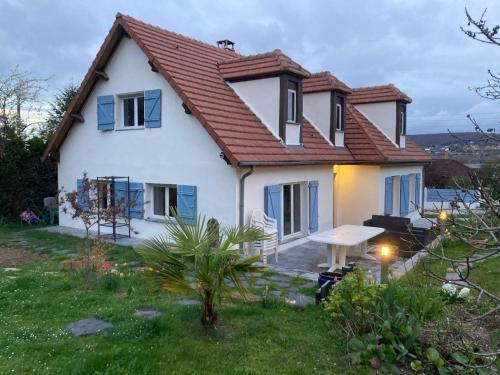 une maison blanche avec une table dans une cour dans l'établissement Chambre meublée dans une maison, à Vernouillet