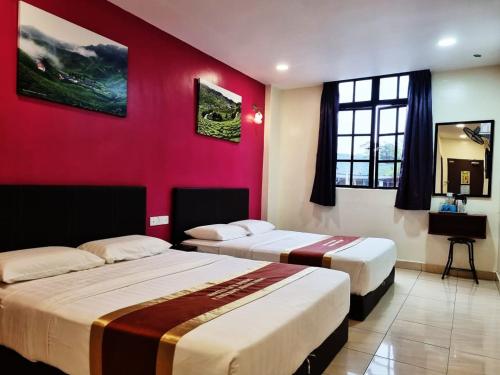 2 Betten in einem Zimmer mit roter Wand in der Unterkunft Hotel Sun Birds in Cameron Highlands