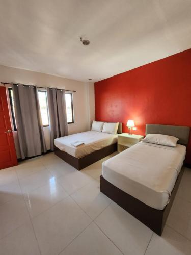 a hotel room with two beds and a red wall at Mantra Pensionne Superior Room in Cagayan de Oro