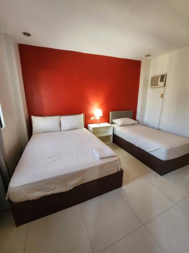 two beds in a room with a red wall at Mantra Pensionne Superior Room in Cagayan de Oro