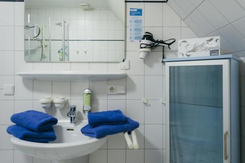 a bathroom with a sink with blue towels on it at Hotel Ekke Nekkepenn in Nebel