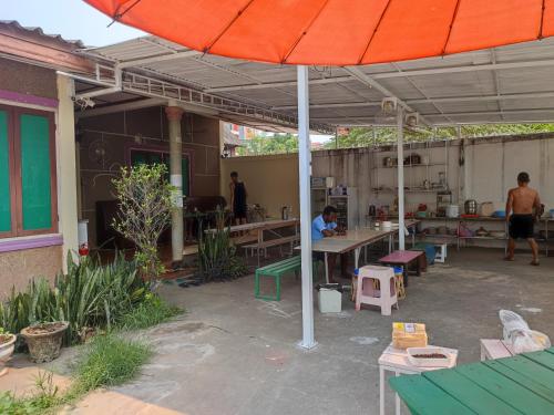 a patio with an orange umbrella and tables and chairs at Vernice Backpacker Hostel in Vientiane