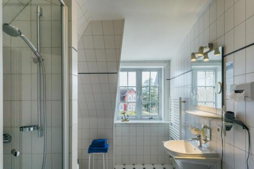 ein Bad mit einem Waschbecken und einer Dusche in der Unterkunft Hotel Ekke Nekkepenn in Nebel