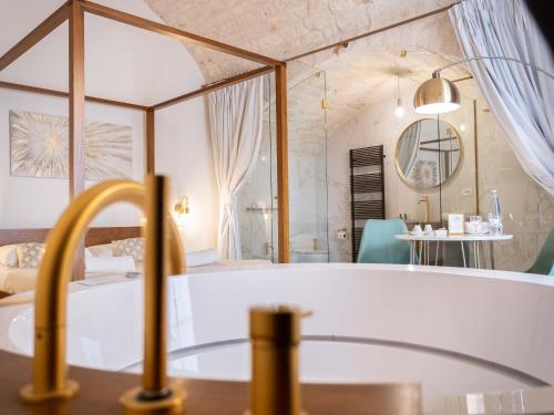 a bathroom with a bath tub and a bedroom at Dama Bianca Boutique Hotel Ostuni in Ostuni