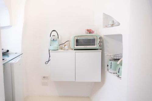 a small white kitchen with a microwave and a toaster at Dama Bianca Boutique Hotel Ostuni in Ostuni